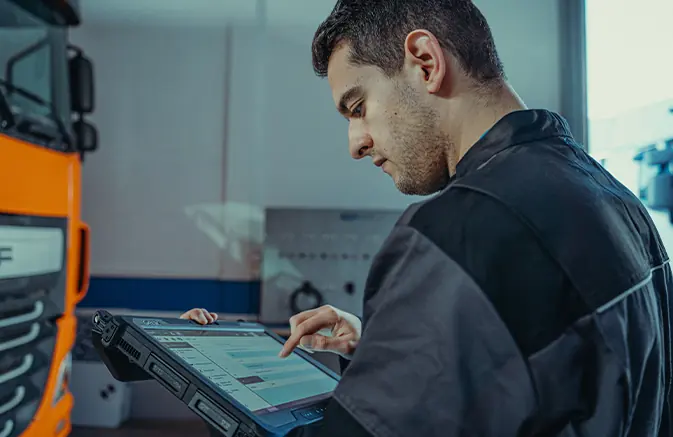 Technician using Jaltest Diagnostics on a rugged tablet next to a truck
